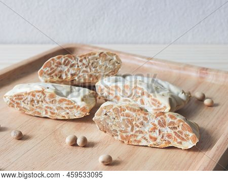 Front View Of Raw Tempeh Or Tempe. Tempeh Slices In Wooden Plate  On Wooden  Table.  Tempeh Is A Tra