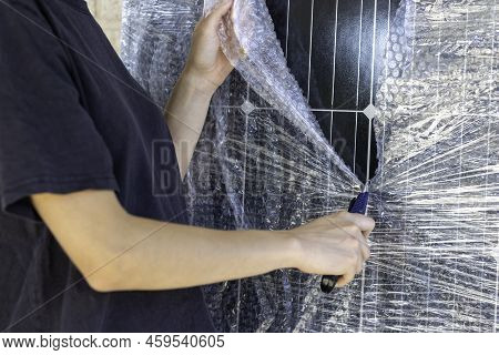 Close Up View Of Unrecognizable Young Working Woman Unwrapping A Photovoltaic Panel With A Cutter