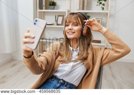 Cheerful Young Blonde Lady In Warm Sweater In Headphones Listen Fav Songs Doing Selfie Video Call Si