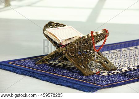 Rehal With Open Quran And Misbaha On Muslim Prayer Rug Indoors