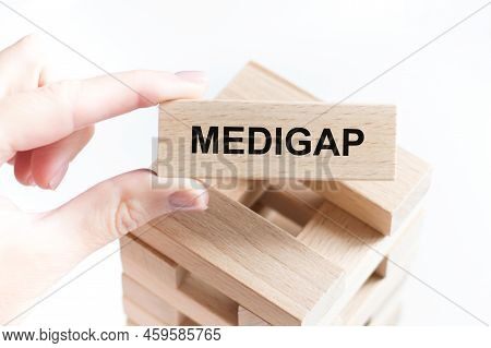 Medigap Inscription On A Wooden Bar In A Human Hand, Sedicine And Business Concept