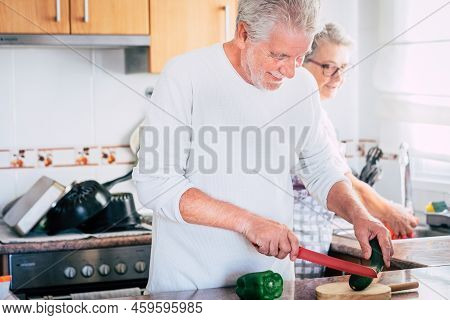 Old Couple Laughing Together - Adult Man Is Kooking And Smilng - Senior Woman Is Washing And Cleanin