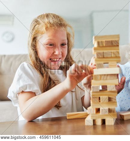 Grandmother And Granddaughter Aplaying With Wooden Brick Toy At Home