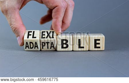 Adaptable Or Flexible Symbol. Businessman Turns Wooden Cubes And Changes The Word Adaptable To Flexi