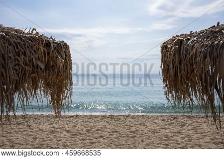 Sea View With Sandy Beach And Umbrellas Made From Palm Tree Leaves