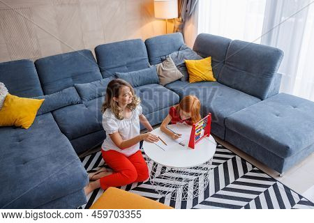 High Angle View Of Mother Helping Daughter With School Project And Homework, Studying Math, Practici