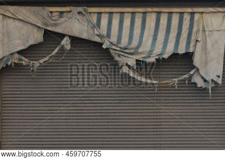 Torn And Ruined Shop Sun Shader At Stor Front. Damaged And Weathered Cloth.