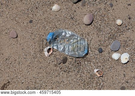 Crumpled Single-use Plastic Bottle On The Beach. Plastic Garbage Thrown By Sea Wave On Shore. Concep
