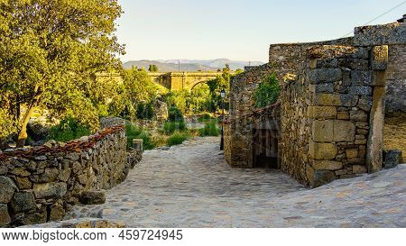 Alley Of An Old Stone Village With Old Houses And Bridge Over The River In The Background, Puente Co