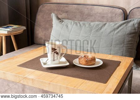 On The Coffee Table In The Living Room, A Cup Of Hot Coffee With A Cream Cake.