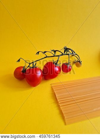 Uncooked Spaghetti And Cherry Tomatoes On Yellow Background