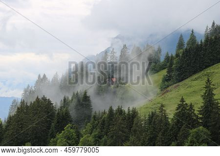 Fog Creeping Up A Mountain Side. Distant View Of Mount Augstmatthorn.