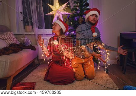 Entangled And Binding Family At The Christmas Tree In The Night Light Garlands. Unfree Parents On Ne
