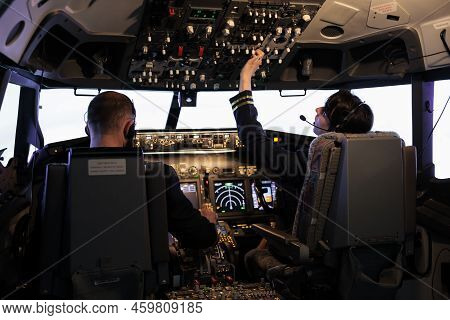 Captain And Female Copilot Getting Ready To Fly Plane And Takeoff With Dashboard Navigation In Cockp