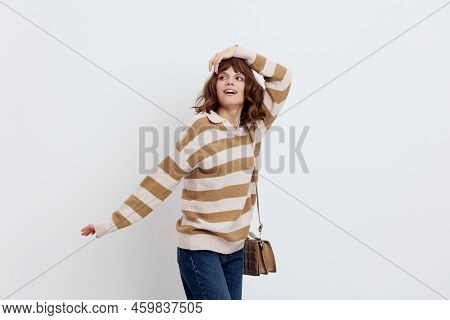 A Pretty Sweet Woman Stands On A Light Background In A Striped Sweater And A Bag On Her Shoulder, Pu