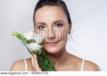 Closeup Portrait Of Attractive Charming Middle Aged Woman With Clean Healthy Skin, Holding Flowers I