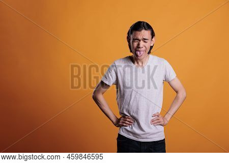Young Asian Man Being Silly, Showing Tongue, Making Funny Grimace. Childish Behavior, Cheerful Teena