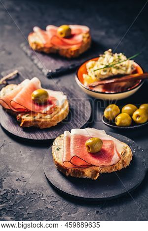 Roasted Bread Or Open Sandwich With Garlic Butter Spread And Serano Ham And Olive On Dark Background