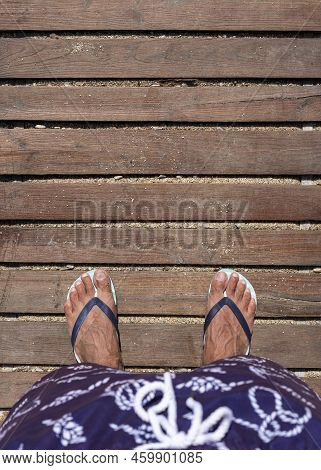 Mans Feet In Flip Flops On Wooden Boardwalk. Top View. Flat Lay. Empty Space, For Text