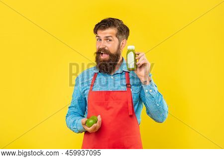 Happy Man In Apron Holding Limes And Juice Bottle Yellow Background, Juicery