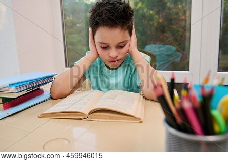 Serious Smart Teenage Schoolboy Reads Text In Textbook While Doing Literature Homework. Erudition. B