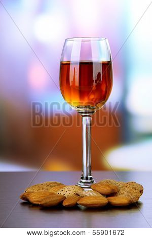 Glass of amaretto liquor and roasted almonds, on bright background