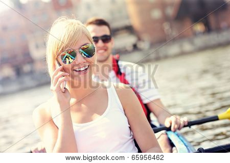 A picture of a young woman talking on the phone in a canoe