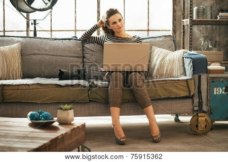 Thoughtful Young Woman With Dslr Photo Camera Using Laptop In Lo