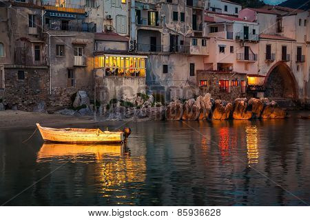 Old Boat Drifting In Cefalu Harbor At Dusk