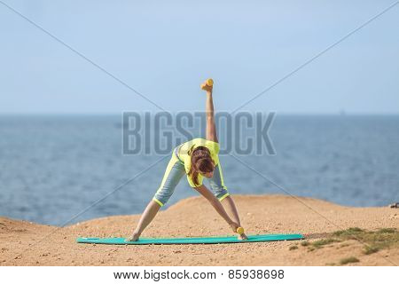 A young woman fitness trainer, shows a set of exercises with dumbbells.