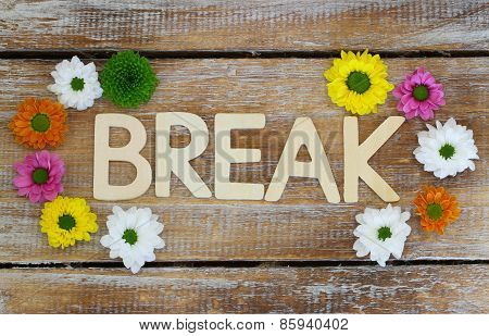 Break written with wooden letters and Santini flowers