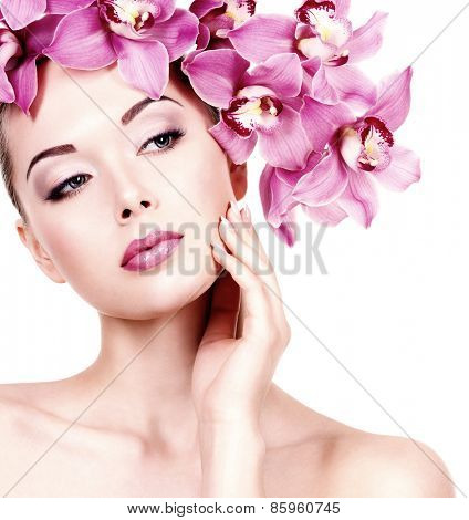 Closeup face of an young beautiful woman with a purple eye makeup and lips. Pretty adult girl with flower near the face.  - isolated on white background