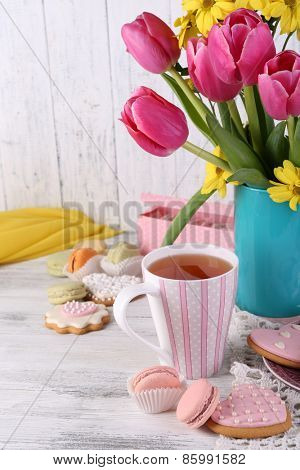Composition of spring flowers, tea and cookies on table close-up