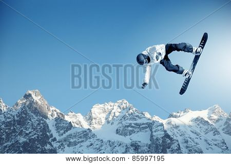 Snowboarder making jump high in clear sky