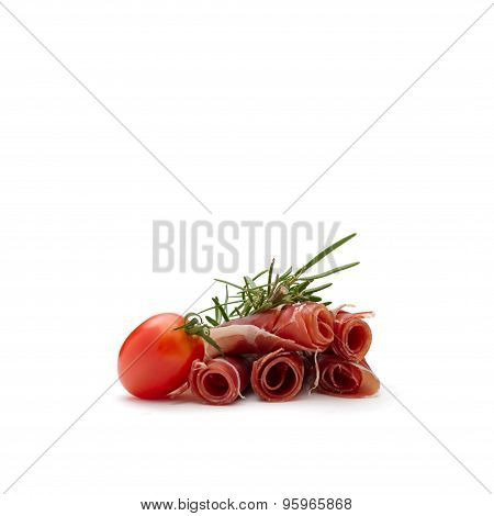Rolled prosciutto ham with a red cherry tomato and a rosemary branch