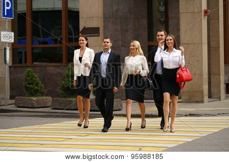 Full length portrait of a Group Of Businesspeople Crossing Summer Street