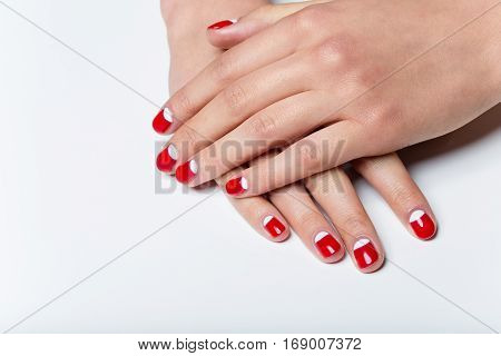 Close-up shot of young femle hands with red and white nail manicure. Copy space.