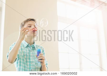 Boy blowing bubbles at home