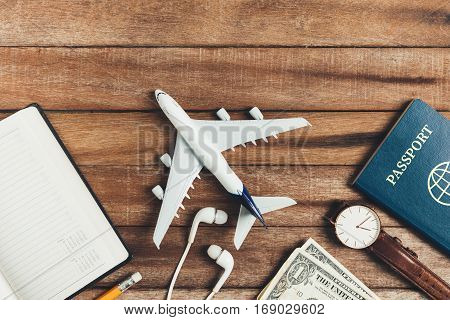 Preparation for Traveling concept pencil watch money passport airplane noted book earphone on a vintage wooden background with copy space.