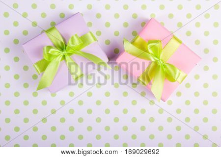 Two gift boxes with green bows on a polka dot background. Copy space.
