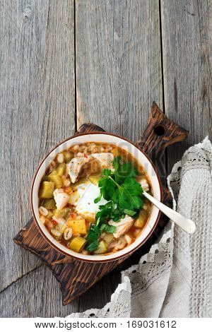 Traditional Russian soup-Rassolnik with pickled cucumber barley chicken tomatoes and parsley in ceramic bowl. Selective focus. Top view.