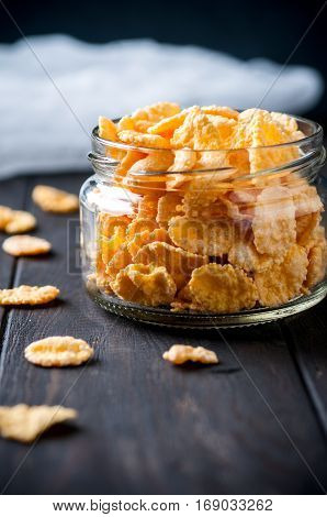 Close up of cornflackes in jar on dark wooden background selective focus vertical. Healthy food concept.