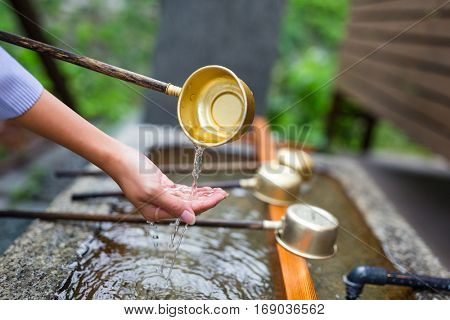 Woman washes her hand in fountain of Japanese temple