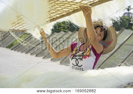 Hanoi, Vietnam - July 13, 2014: Unidentified woman dries vermicelli made from rice flour. Vermicelli is an ingredient of Vietnamese noodles soup.