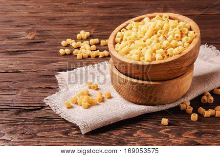 Raw pasta ditalini in a wooden bowl on the table