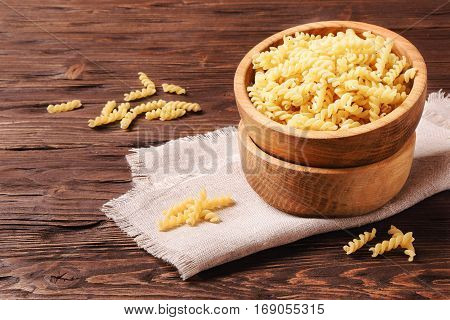 Raw pasta rotini in a wooden bowl on the table