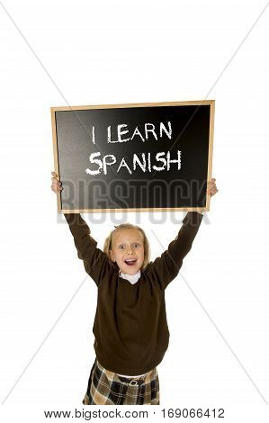 7 8 years old little beautiful blond schoolgirl smiling happy and cheerful holding and showing small blackboard with text I learn Spanish in language education concept isolated white