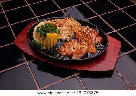 Fried fish with rice on the black cast-iron plate