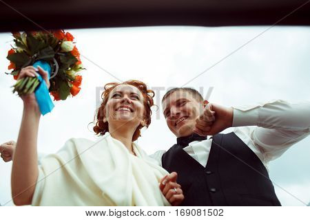 A View From Below On A Smiling Bride And Groom Standing In A Hatchway