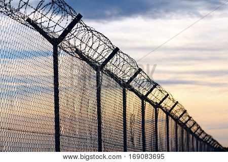 Silhouette of Barbed Wire fence against a Cloudy Sky